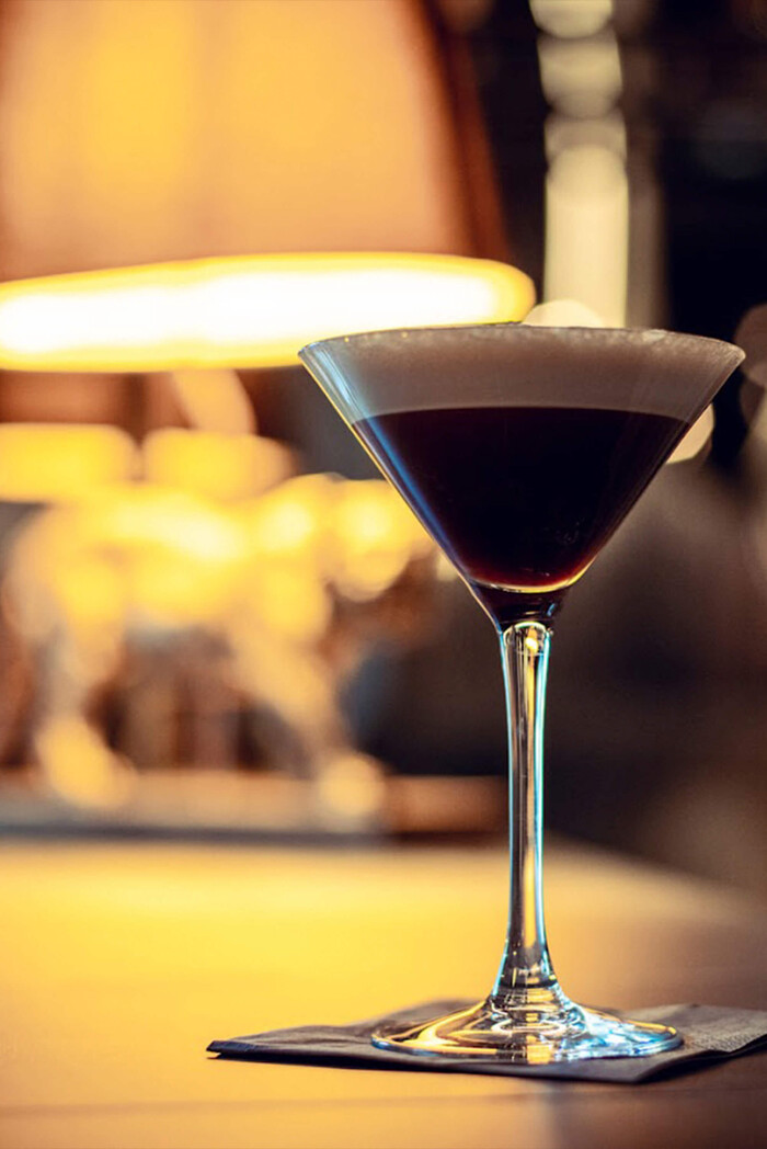 Dunkler Espresso Martini auf Bartisch mit stimmungsvoller Beleuchtung